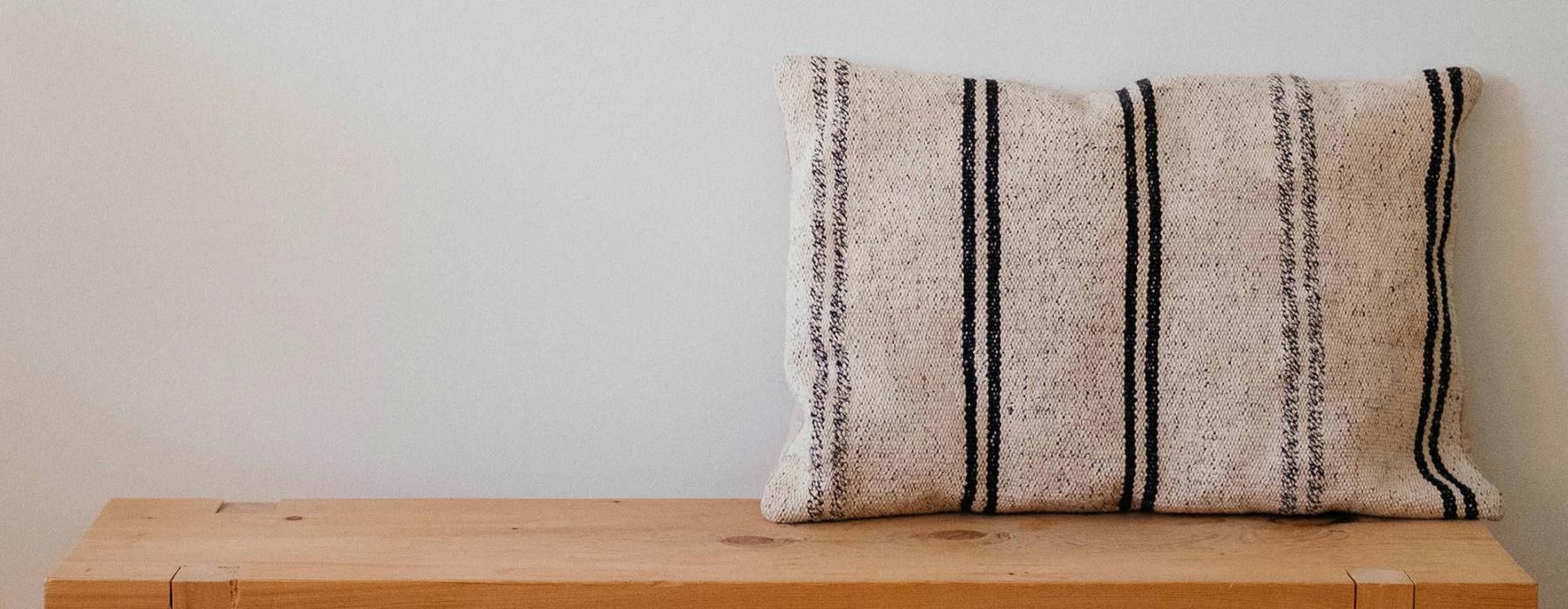 a wooden bench with a striped pillow on it