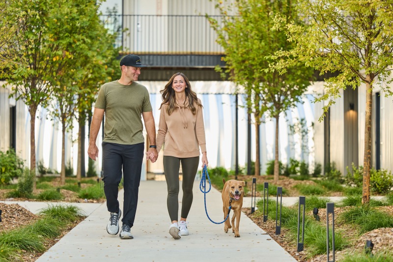 Couple walking their dog along a landscaped pathway at a pet-friendly apartment community