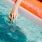 woman dangles her hand in the pool as she floats in an inflatable vessel